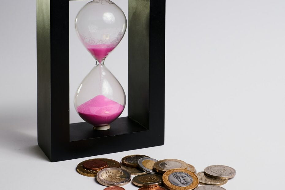 An hourglass next to a pile of coins